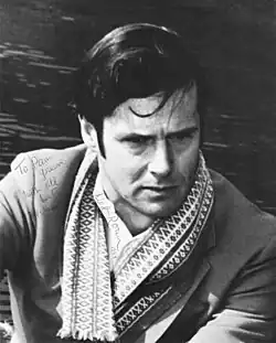 Middle-aged man looking into the distance, with serious expression and ornate scarf