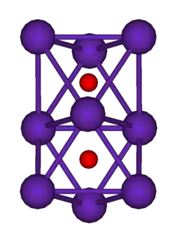 The ball-and-stick diagram shows two regular octahedra which are connected to each other by one face. All nine vertices of the structure are purple spheres representing rubidium, and at the centre of each octahedron is a small red sphere representing oxygen.